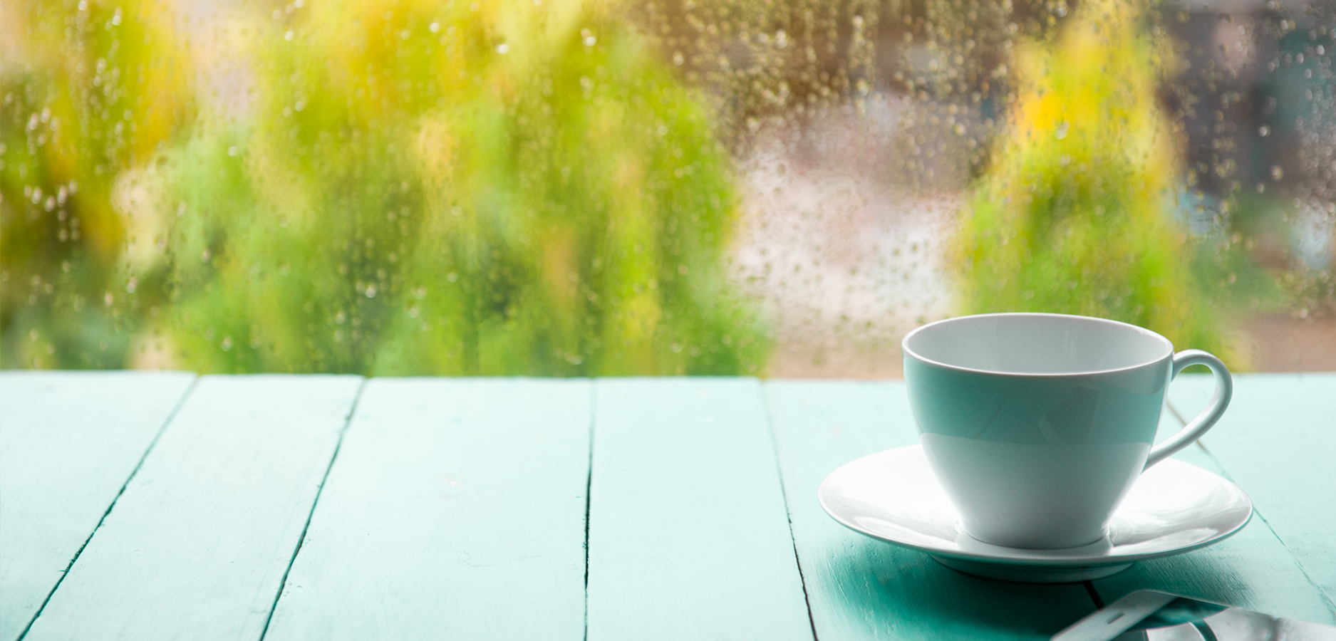 a tea cup on a table in front of a rainy window