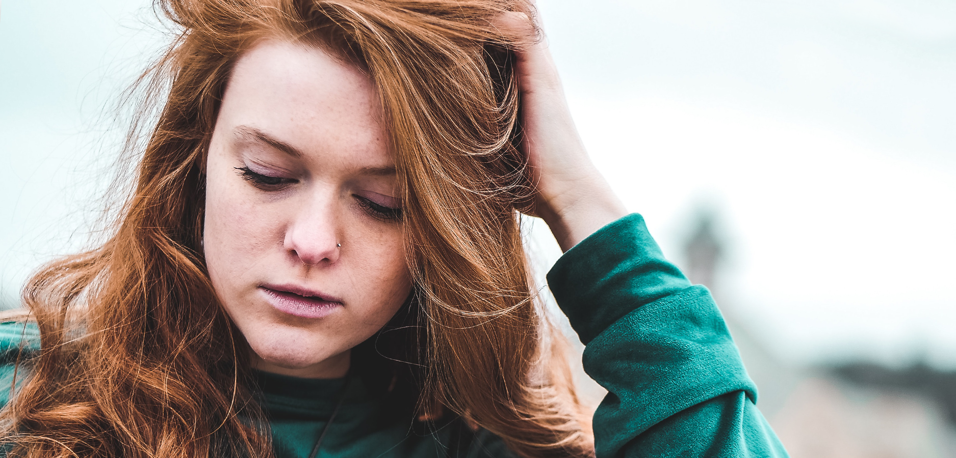 young woman holding her hair back and looking down